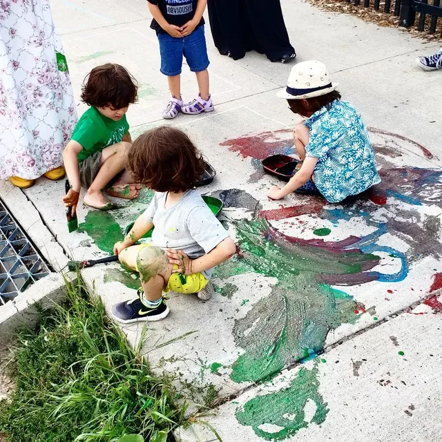 Young children making a colourful mural with eco-paint