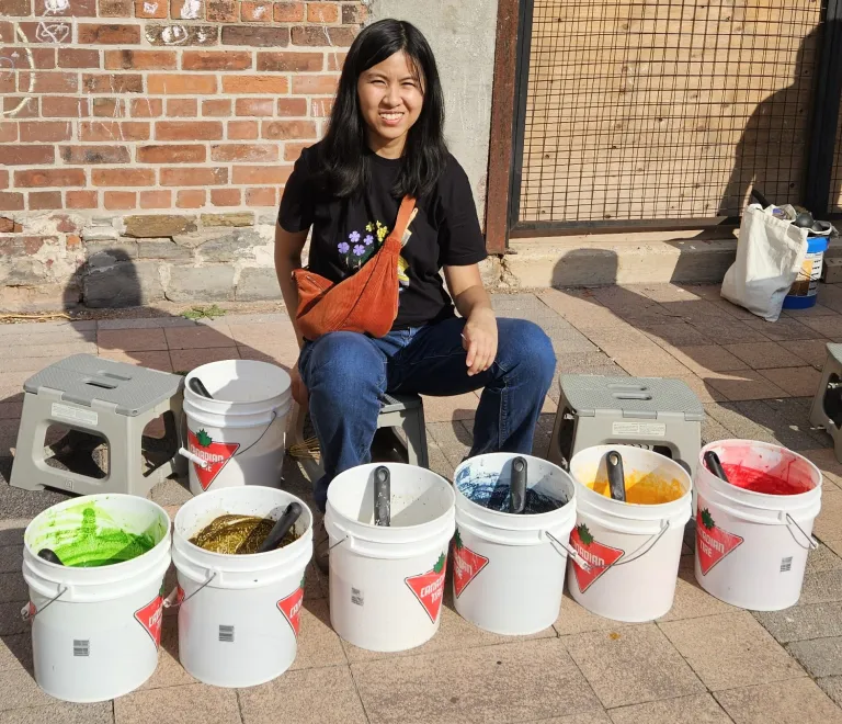 A Splash on Earth team member beside buckets of eco-paint