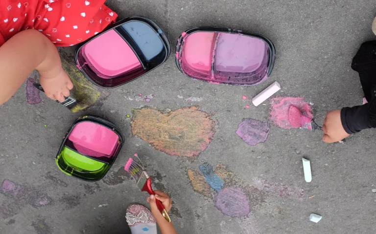 Children painting colourful designs on pavement during an event